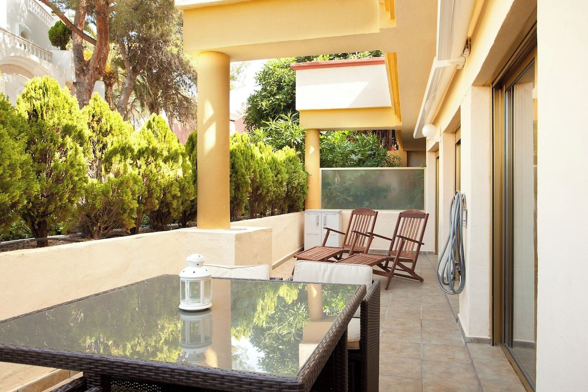An outdoor seating area with a glass table, wicker chairs, and a lantern.