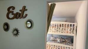 Een kinderkamer met stapelbedden, een spiegel aan de muur en decoratieve wanddecoraties.