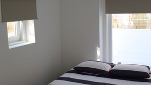 Een slaapkamer met een bed, een raam met uitzicht en een hangende lamp.