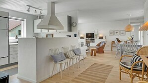 Una cocina moderna con armarios blancos, una isla grande e iluminación colgante.