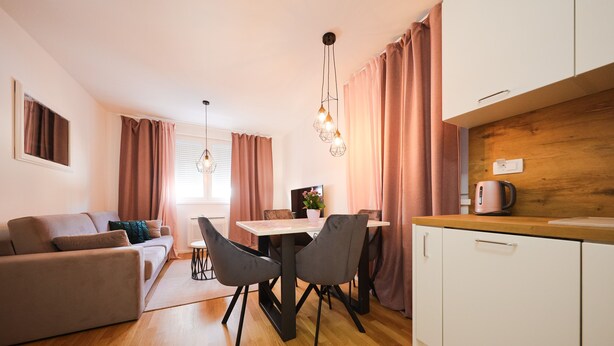 A modern living room with a sofa, dining table, and chairs. There is a kitchen area with cabinets and a countertop. - Cherry Apartment for Families and Couples with Free Parking (Zadar)