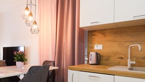 A modern kitchen with white cabinets, a wooden countertop, and a built-in sink. There is a dining table with chairs and a potted plant. - Cherry Apartment for Families and Couples with Free Parking (Zadar)