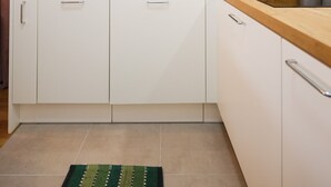 A modern kitchen with white cabinets, a wooden countertop, a stainless steel sink, and a kettle. - Cherry Apartment for Families and Couples with Free Parking (Zadar)