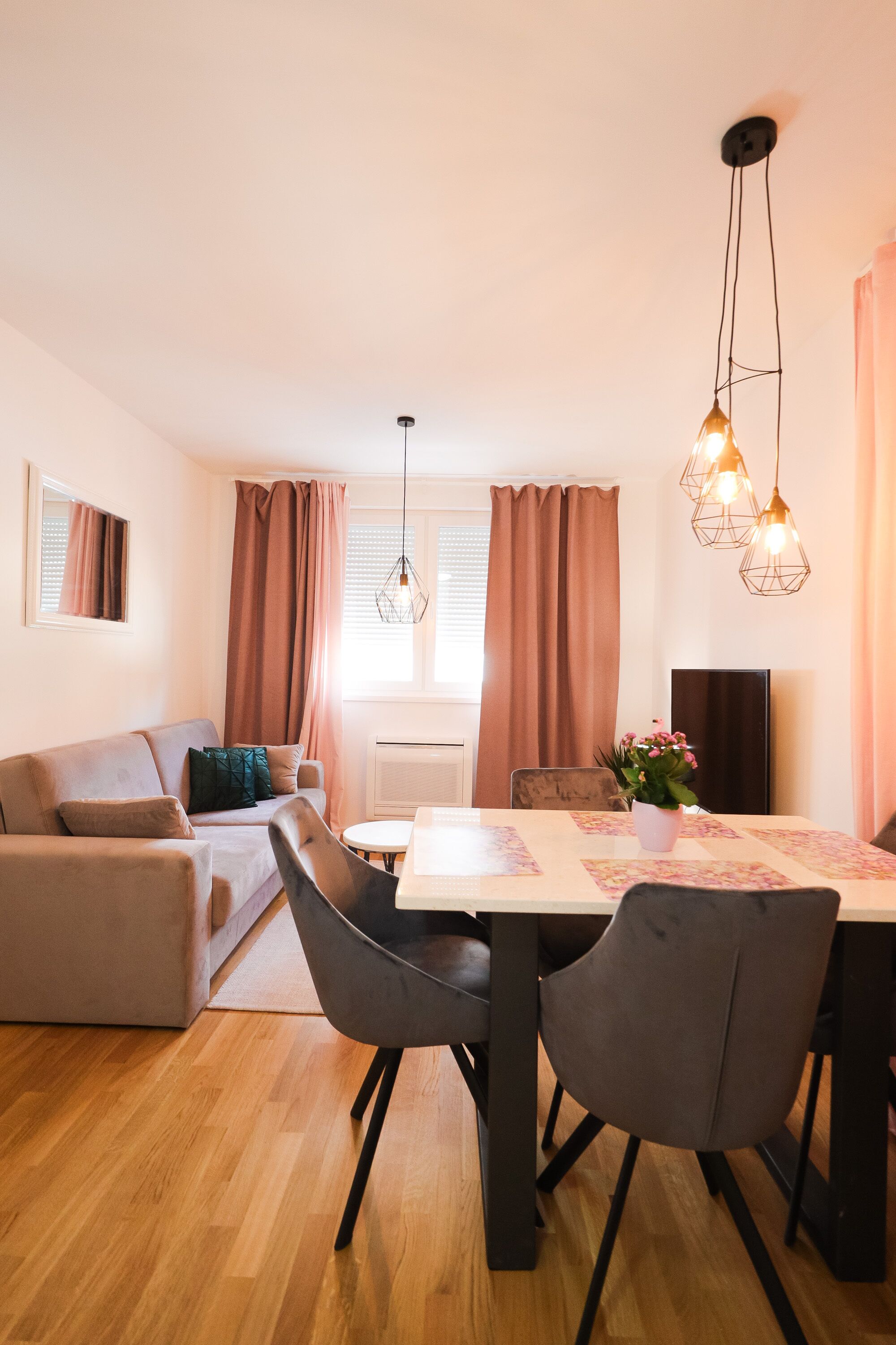 Ein modernes Wohnzimmer mit einer Couch, einem Esstisch, Stühlen und einer Pendelleuchte.