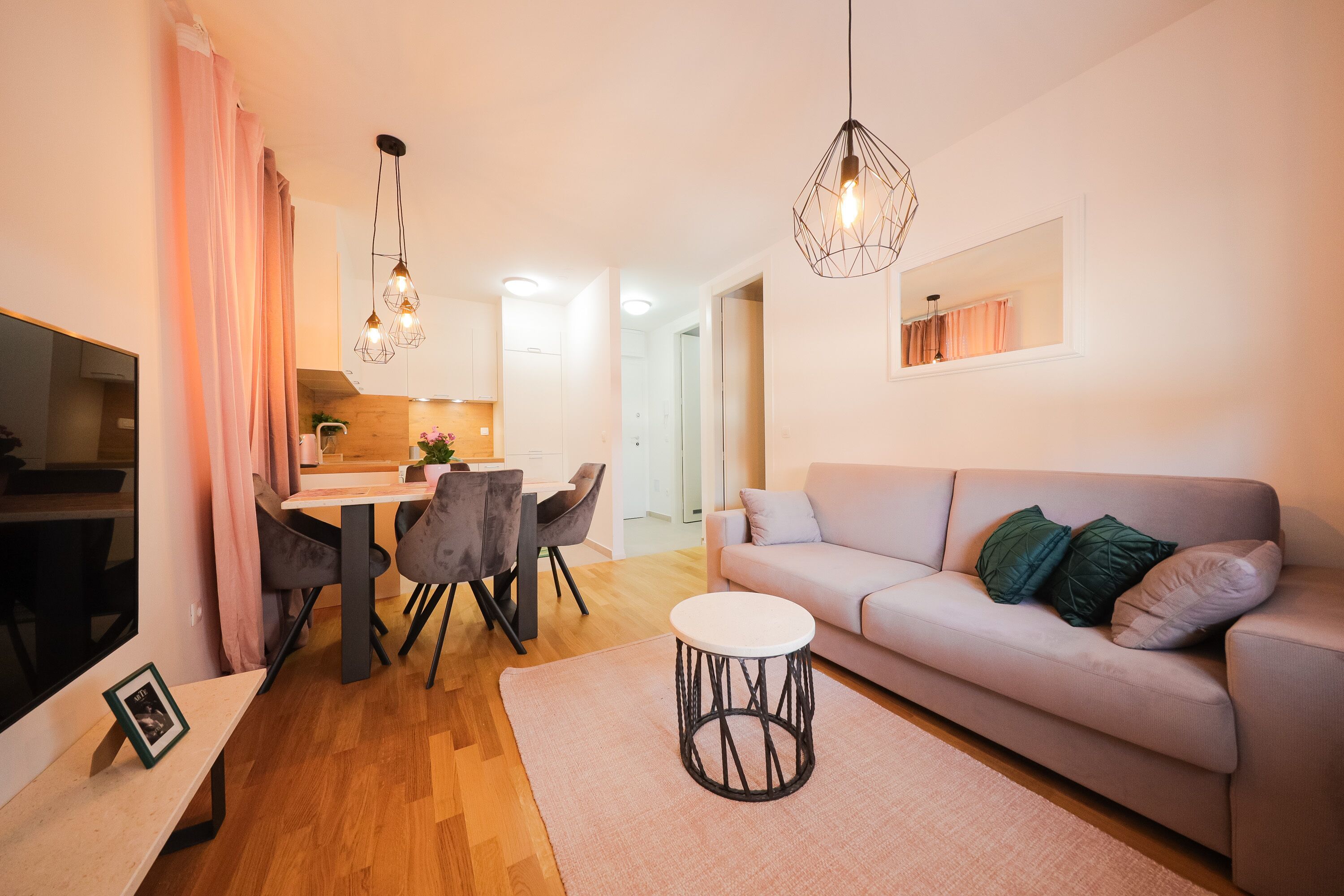 A modern living room with a sofa, dining table, chairs, and a round coffee table.