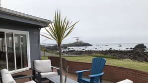 A patio with outdoor furniture, a small tree, and a view of the ocean. - Ocean Front Home with private beach access.   (Crescent City)