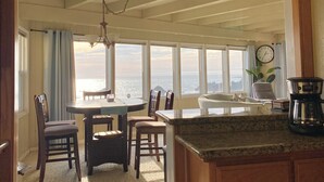 A kitchen with a dining area, large windows, and a view of the ocean. - Ocean Front Home with private beach access.   (Crescent City)