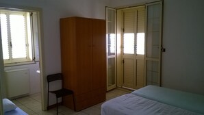 Une chambre à coucher avec un lit, une armoire, une chaise et un radiateur.