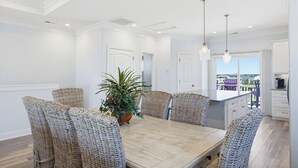 A dining area with a wooden table and wicker chairs, a potted plant, and a view of the outside.