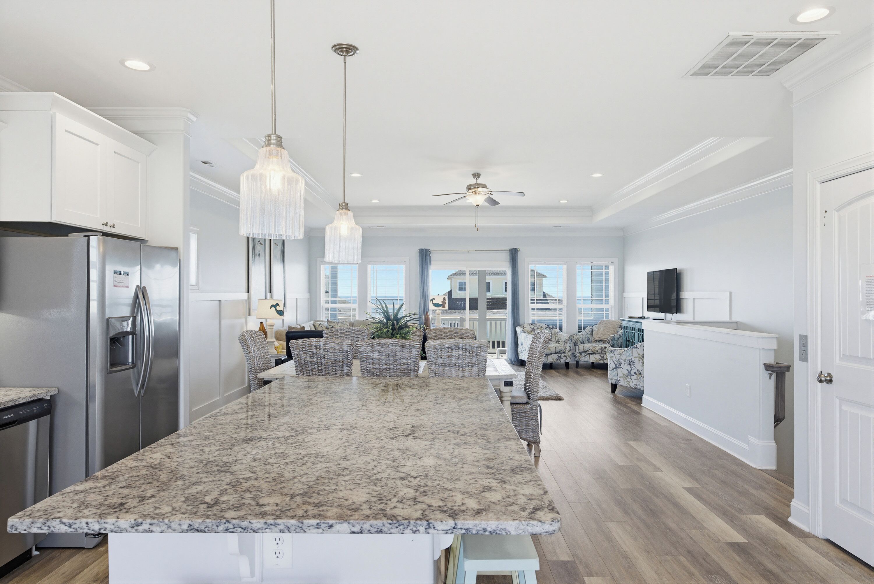 A kitchen with a granite countertop, stainless steel appliances, and pendant lighting.
