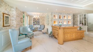 A spacious lobby with a reception desk, seating area, and a bookshelf. - Hotel Orion (Lefkada)