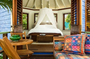 A bedroom with a canopy bed, wooden furniture, and a view through the window.