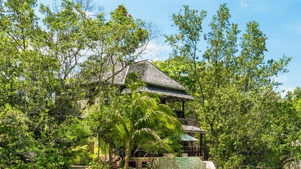 Un resort con piscina, sillas de descanso y un muro de piedra.