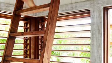 Una escalera de madera apoyada en una ventana con persianas horizontales.