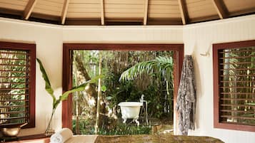 Relax in comfort with a central bed and a view of lush greenery through the large window.