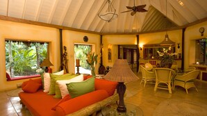 Un salón espacioso con un sofá grande, una mesa de centro de cristal y un comedor con sillas de mimbre.