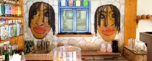 A bar area with a stone wall, shelves with bottles, a window, and a sink.