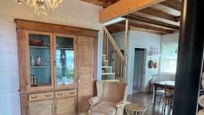 Ein gem ütliches Wohnzimmer mit Kamin, einer Holzkabine mit Glastüren, einem Leopardenmuster-Sessel und einem runden Teppich mit Blätermotiv.