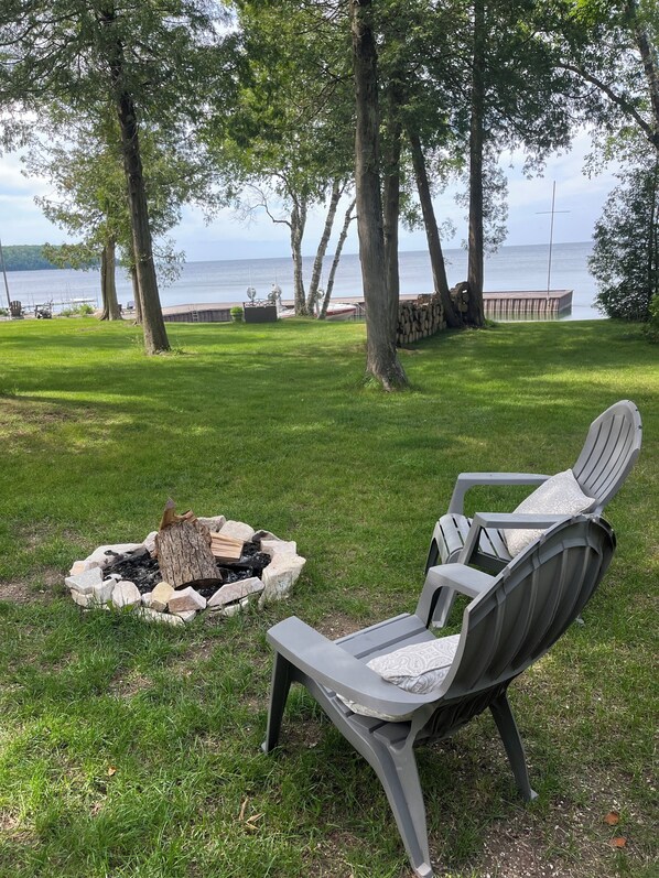 A grassy outdoor area with a fire pit and a chair.