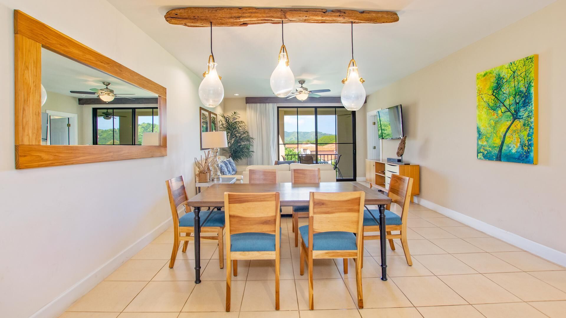 A dining area with a wooden table and chairs, a large mirror, and a ceiling fan.