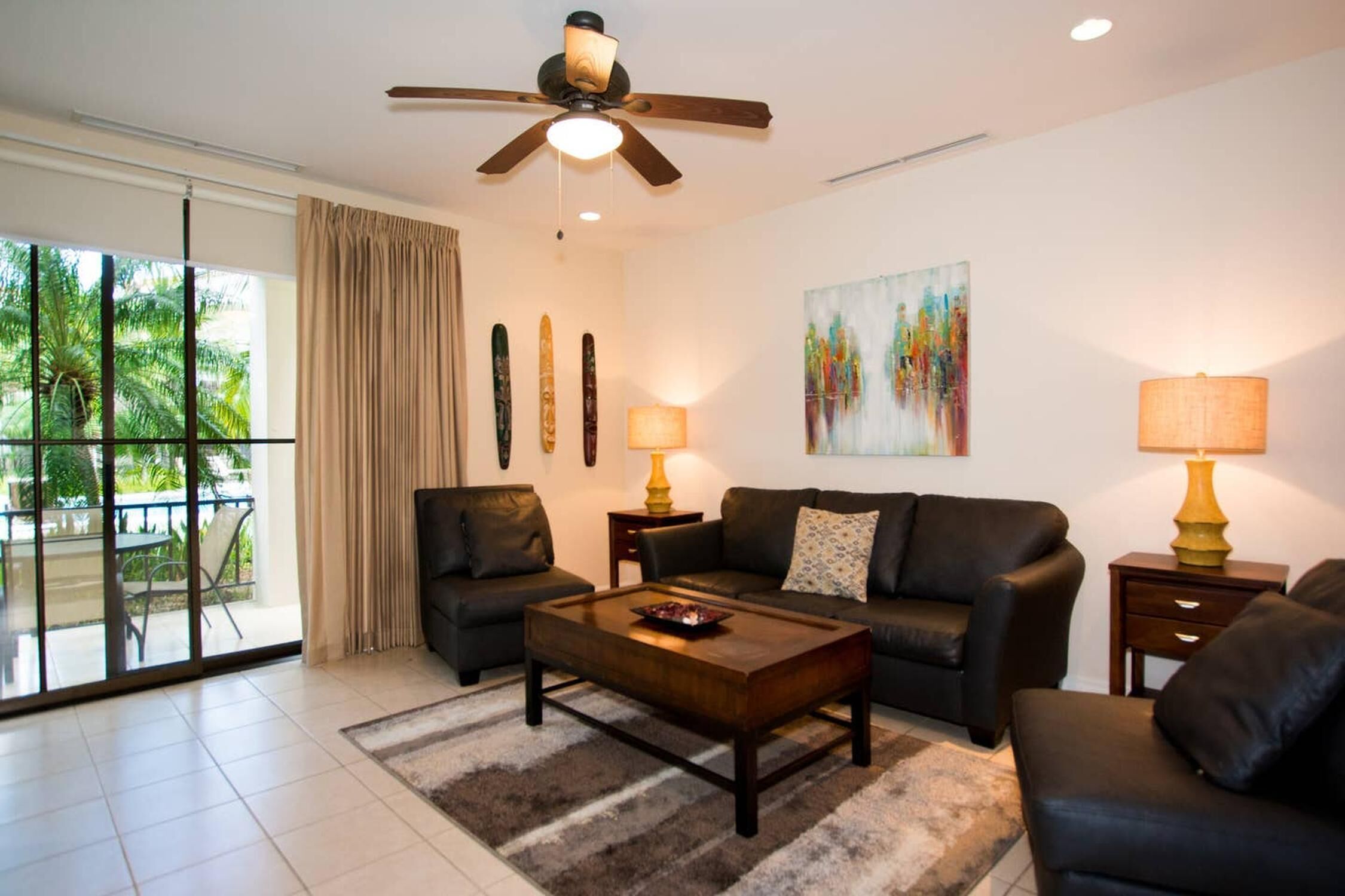 A modern living room with a ceiling fan, two sofas, a coffee table, and a painting on the wall.