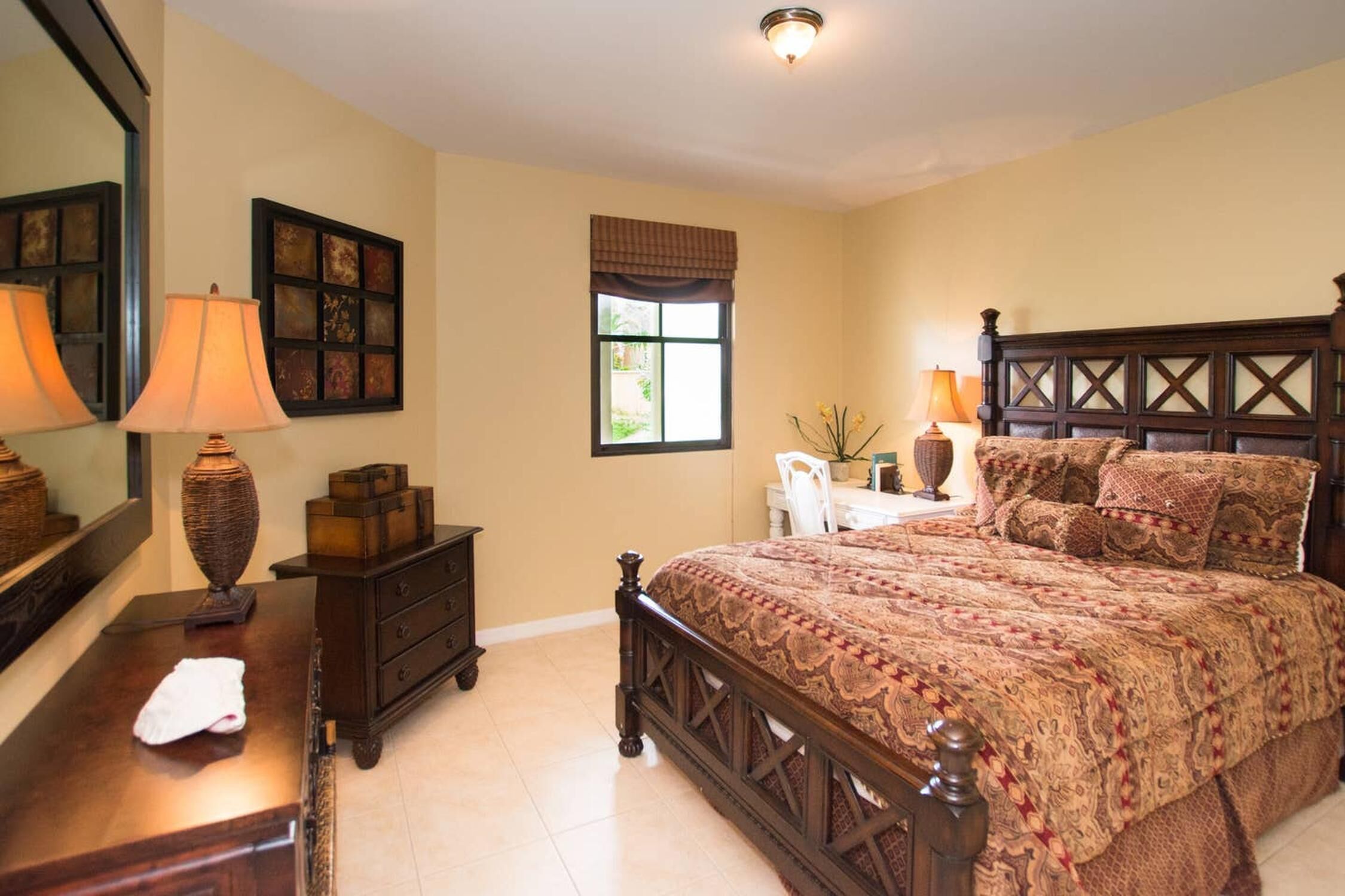 A bedroom with a large bed, a dresser, a mirror, and a window.