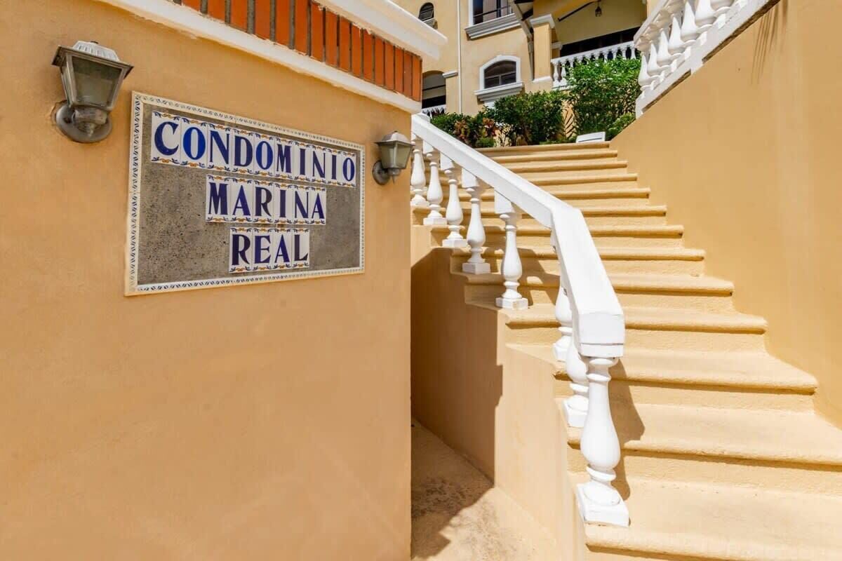 A staircase with a sign reading 'CONDOMINIO MARINA REAL' on a beige wall.
