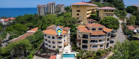 A residential area with multiple buildings, a swimming pool, and a view of the sea.