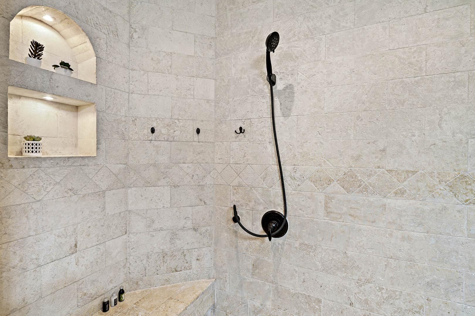 Une douche équipée d'un pommeau de douche à main fixé sur un mur carrelé.