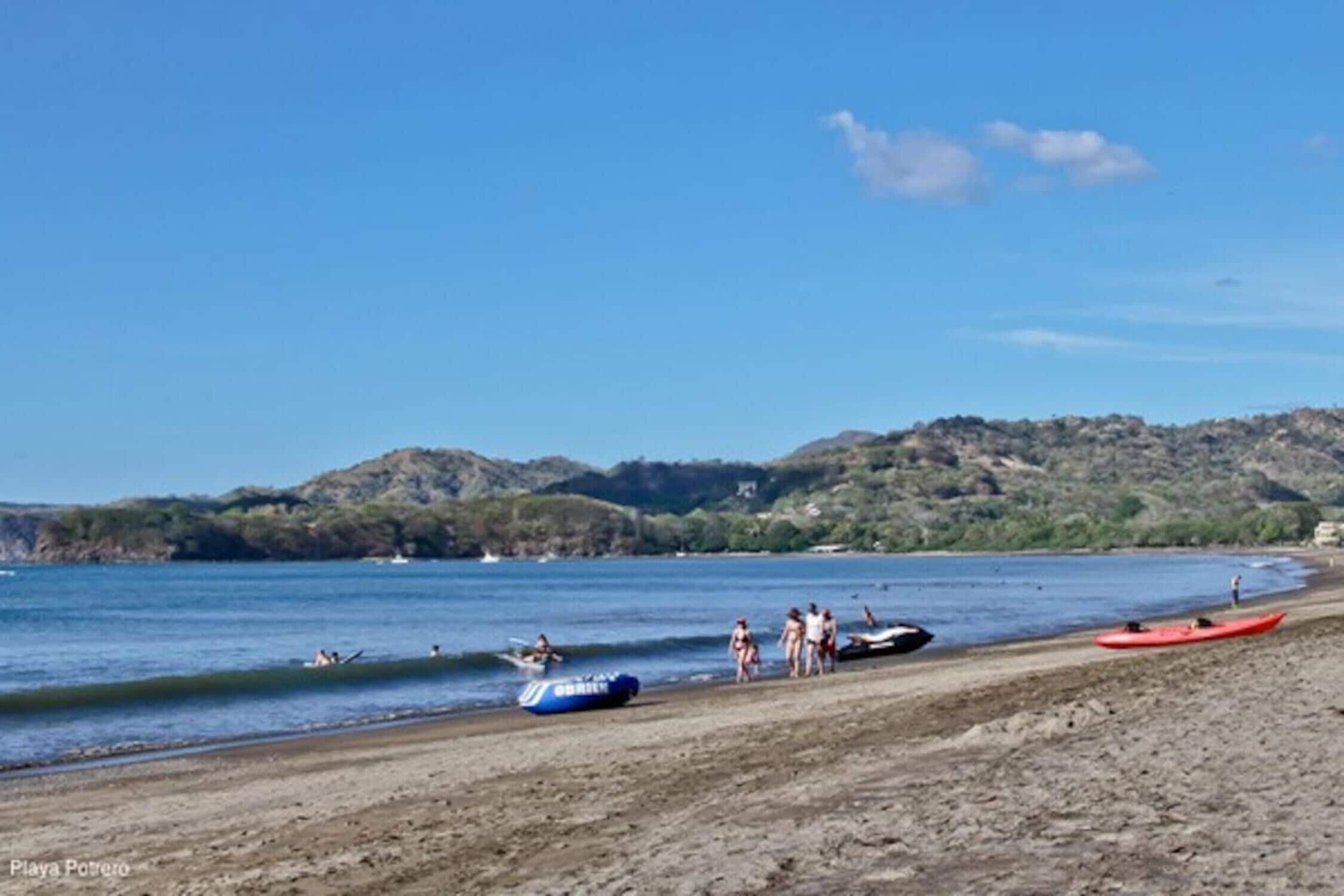 Una playa con kayak y gente cerca del agua.