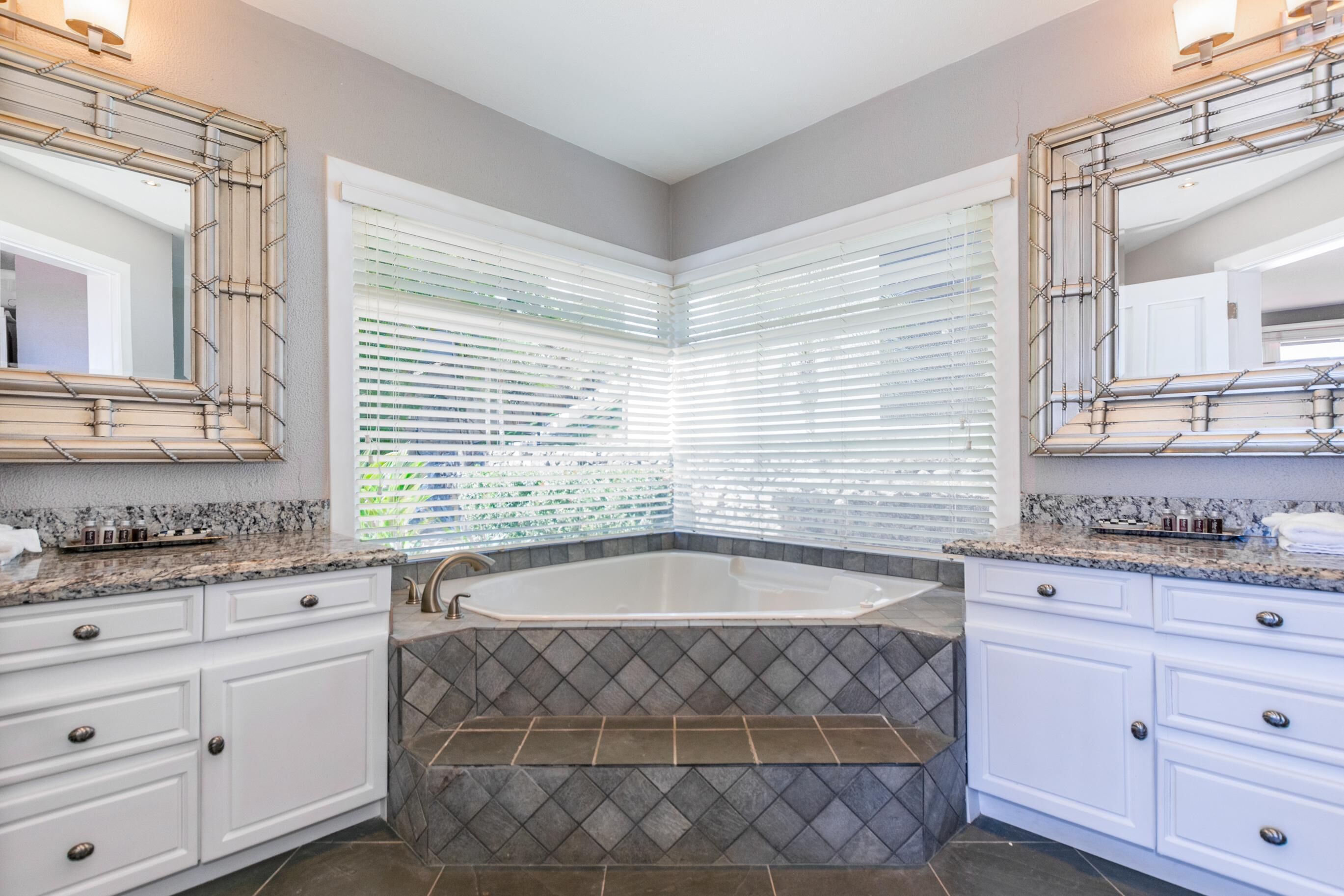 Un baño moderno con una bañera independiente, muebles blancos y un espejo grande.