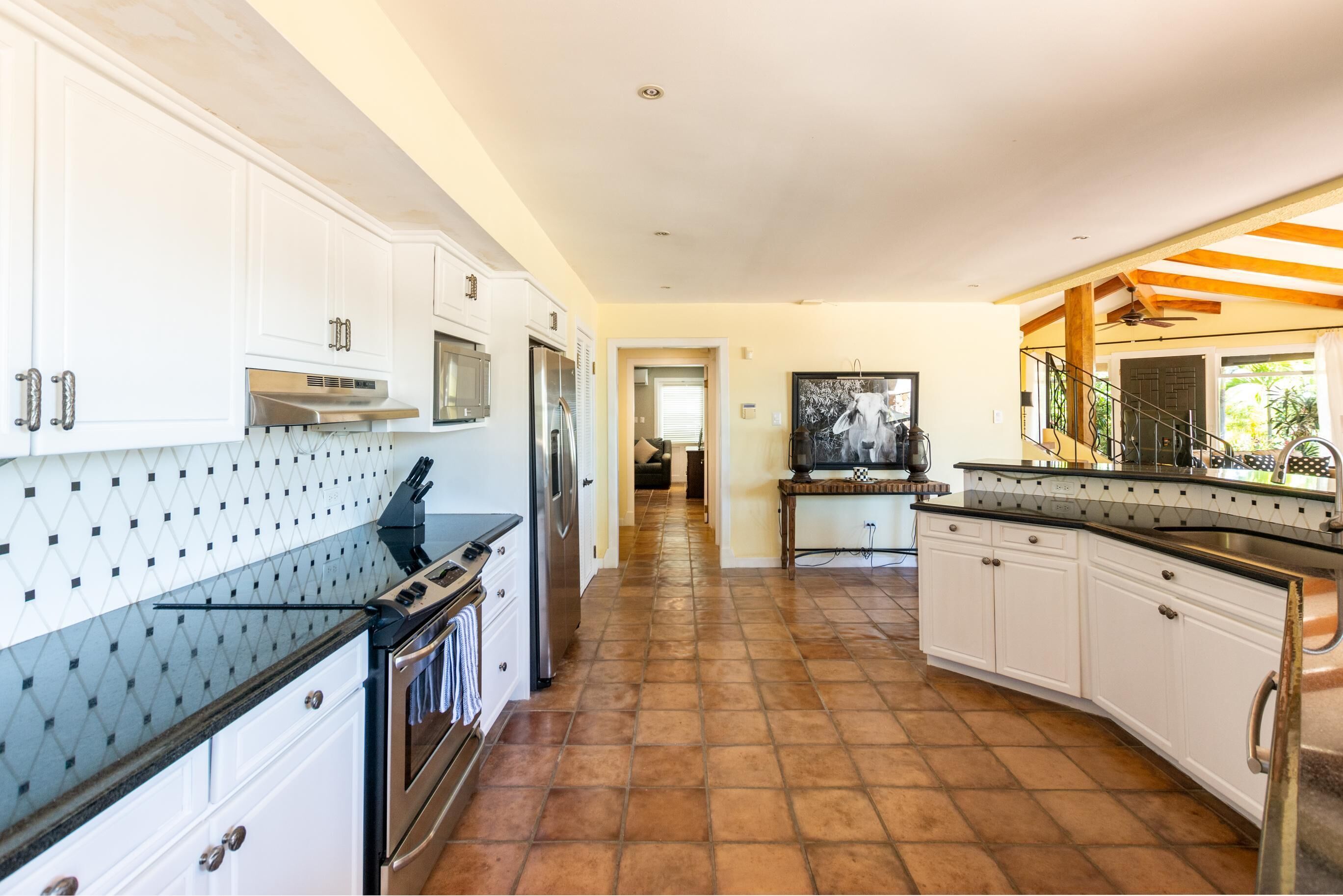Cocina con armarios blancos, encimera negra y salpicadero de azulejos.