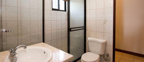 Une salle de bain équipée d’un lavabo, de toilettes et d’une douche à parois en verre.