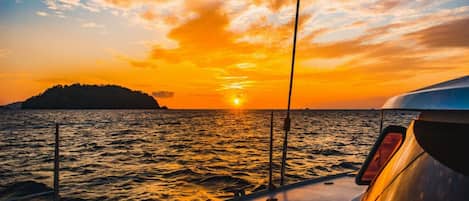A boat deck with a view of a sunset over the ocean.