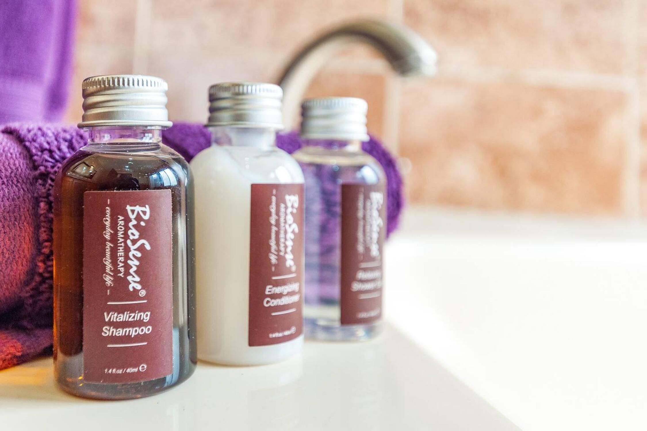 Tre shampoo flasker på en badeværelseshylde.