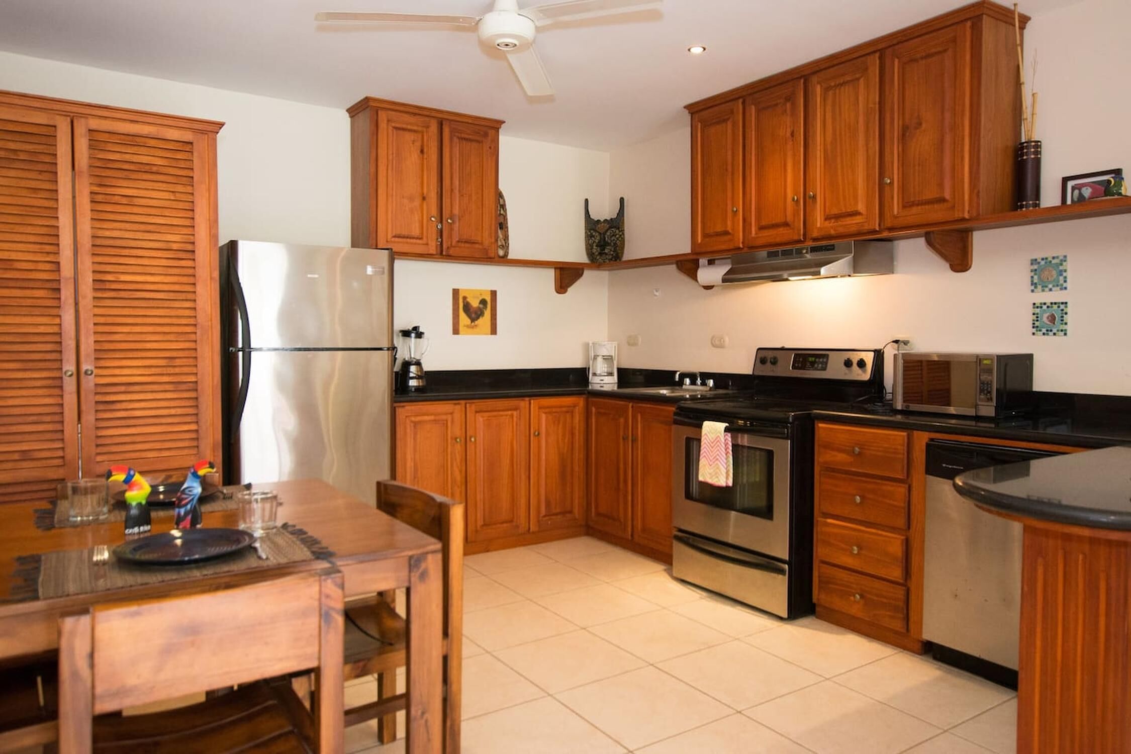Une cuisine avec des meubles de rangement en bois, un réfrigérateur, une cuisinière et un four à micro-ondes.