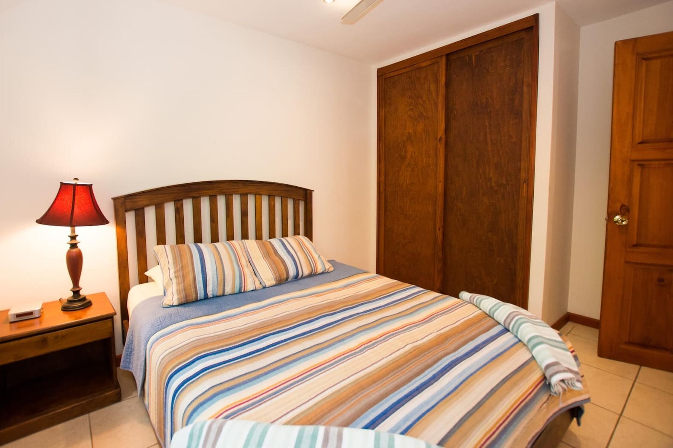 Une chambre à coucher avec un lit, une table de chevet, une lampe et une armoire.