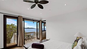 Une chambre à coucher avec un lit, une table de chevet, une table avec des chaises et une vue sur la mer.