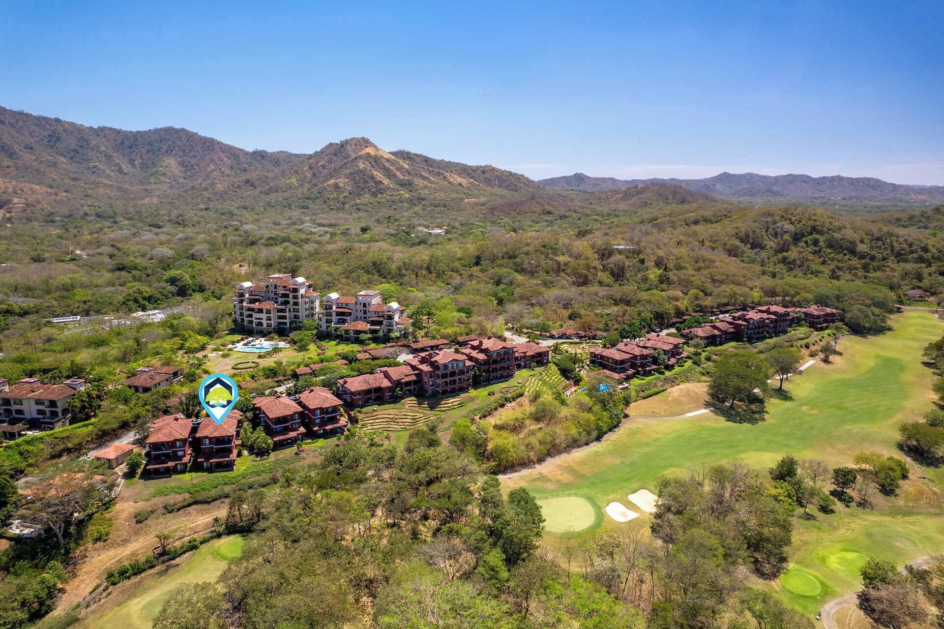 A resort with multiple buildings, a golf course, and mountainous terrain in the background.