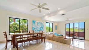 A spacious living area with a dining table, sofa, and large windows with a view. - Recently Renovated Luxury Condo with Resort-Style Beach Club Access and Ocean Views (Cabo Velas)