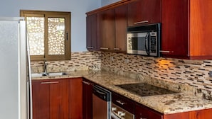 A kitchen with wooden cabinets, a stainless steel microwave, and a granite countertop. - Coastal-Inspired Condo w/ Infinity Pool & Oceanview Terrace (Cabo Velas)