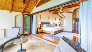A spacious bedroom with a large bed, a sitting area with a table, and a balcony. - Stylish Split-Level Condo with a Shaded Terrace, Direct Beach Access, and Resort-Style Community Amenities (Cabo Velas)