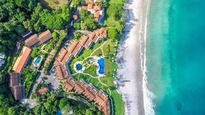 An aerial view of a resort with multiple buildings, a beach, and several swimming pools. - Stylish Split-Level Condo with a Shaded Terrace, Direct Beach Access, and Resort-Style Community Amenities (Cabo Velas)
