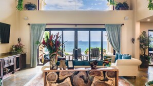 A spacious living room with a large window overlooking the ocean, a wooden coffee table, and a sofa. - Stunning Luxury Mansion in Playa Flamingo with Six Bedrooms and Beachfront Access (Cabo Velas)