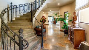 A grand staircase with a wrought iron railing leading to a landing area with a vase of flowers. - Stunning Luxury Mansion in Playa Flamingo with Six Bedrooms and Beachfront Access (Cabo Velas)