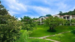 A lush green landscape with a building featuring a central courtyard and multiple balconies. - Nicely decorated 3rd-floor beauty with pool-view balcony in Coco (Sardinal)