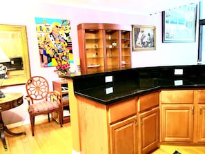 Cozy kitchen area with a wooden chair, table, and lamp, featuring a warm and inviting atmosphere.