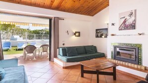 A living room with a wooden ceiling, a green sofa, a wooden coffee table, and a fireplace. - Villa Jacaranda V3 by Interhome (Albufeira)