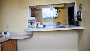 A reception desk with a no pets sign, a clock, and a telephone. - The Perrysburg Budget Inn (Perrysburg)