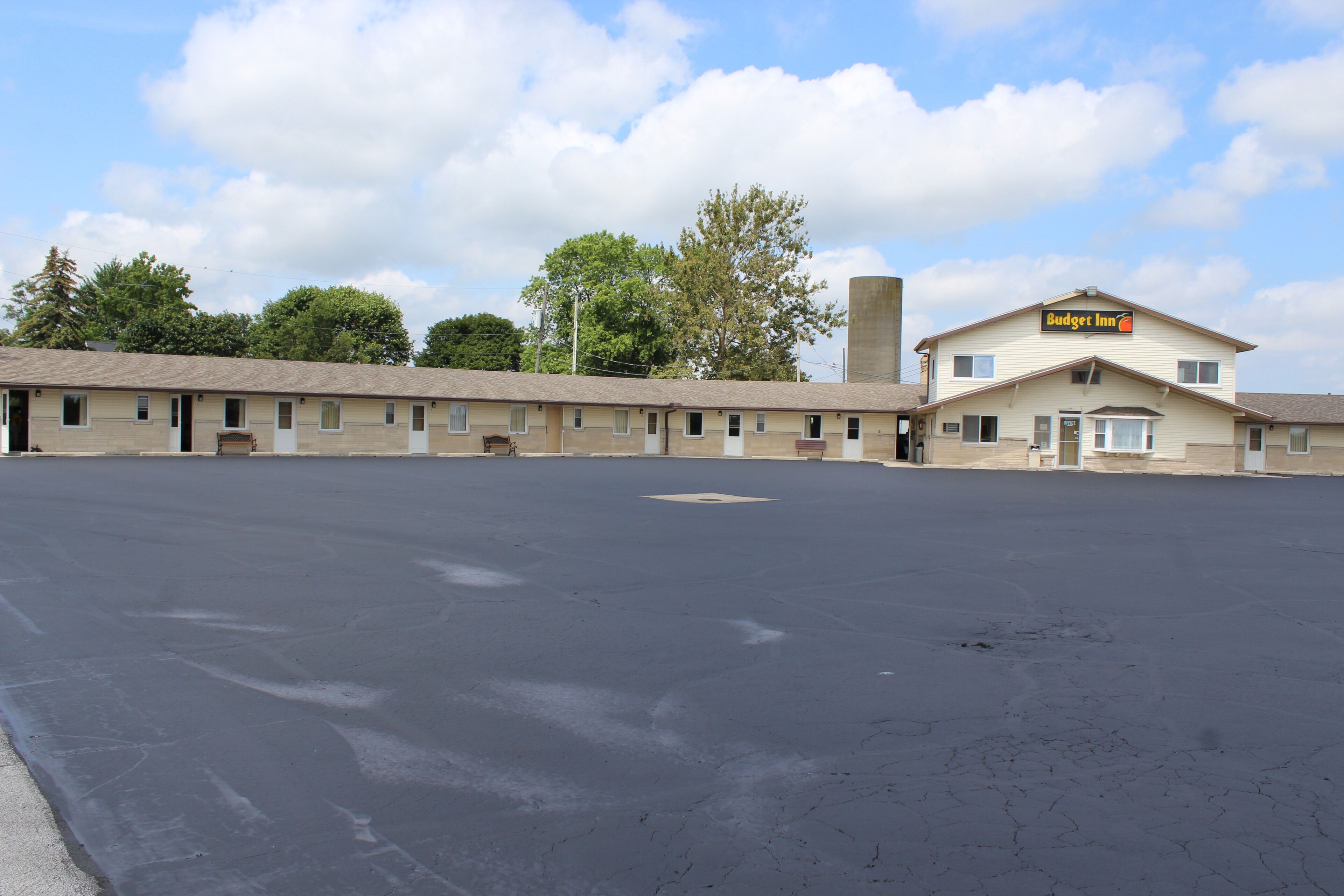 A motel with a large parking lot, a single-story building, and a sign reading 'Budget Inn.'